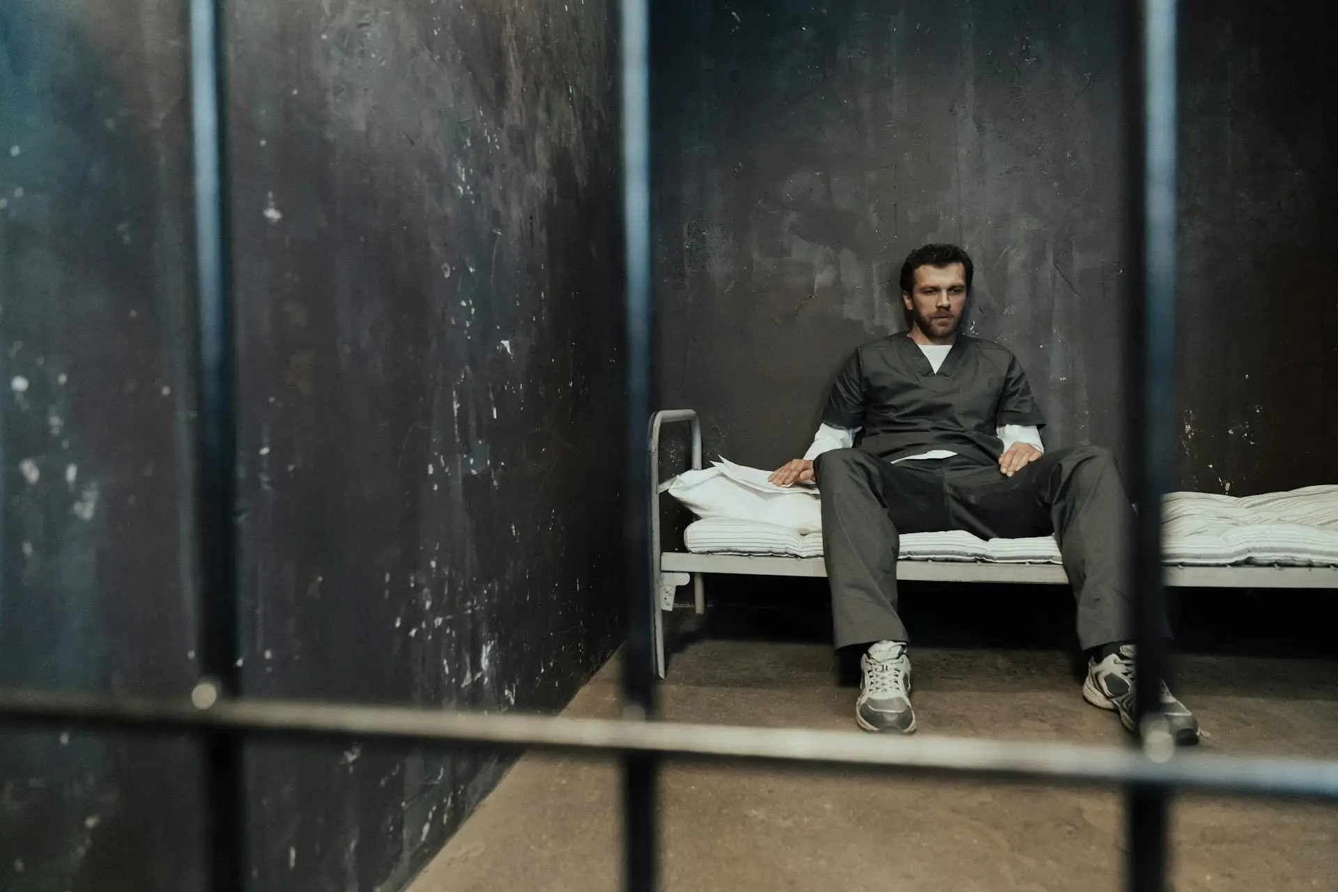 Man-Sitting-on-Bed-in-Prison-Cell.webp